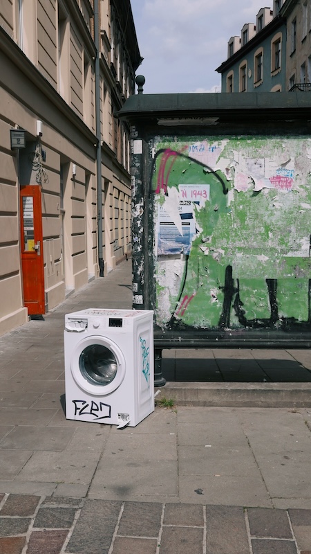 A washing machine sits on a sidewalk