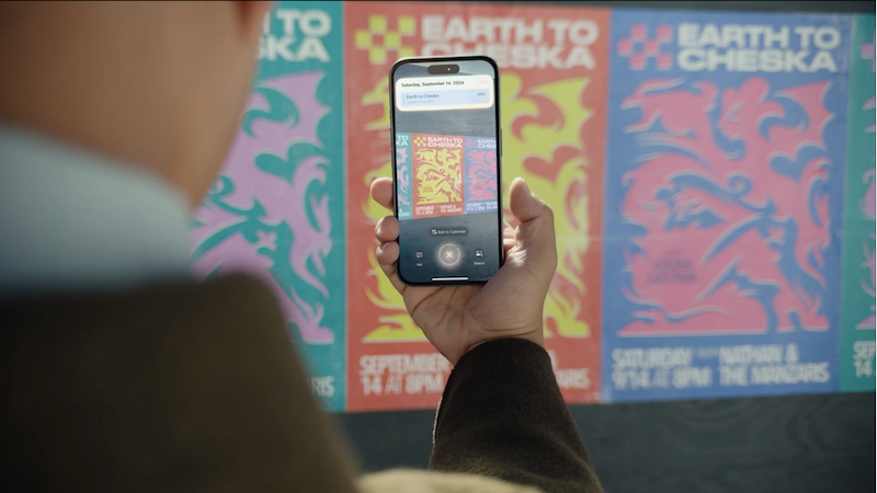 A man taking a picture of a poster with his iPhone. The iPhone offers to add the advertised event to his calendar.