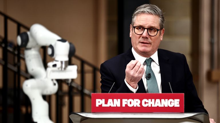 Keir Starmer with a "PLAN FOR CHANGE" sign and a robot arm for some reason