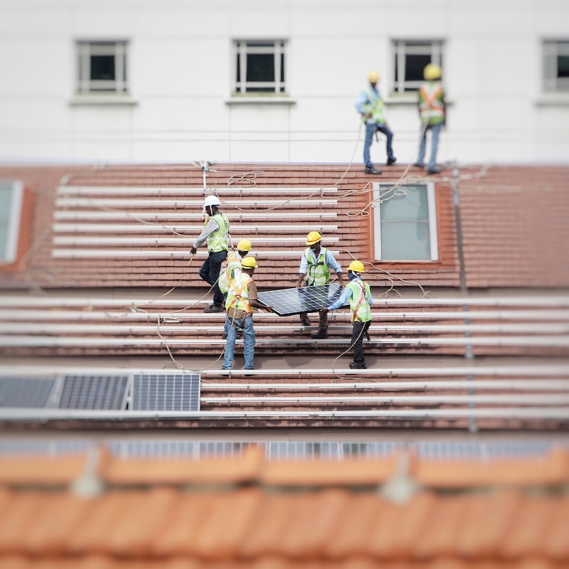 Workers installing solar panels on a roof